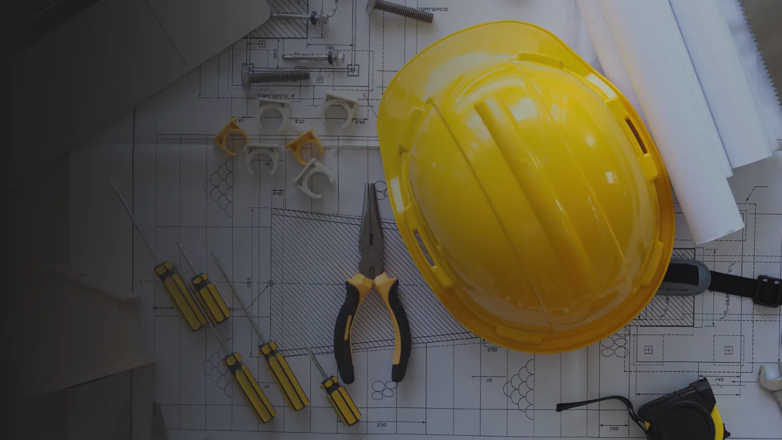 A hard hat and drawings on an engineer's desk.